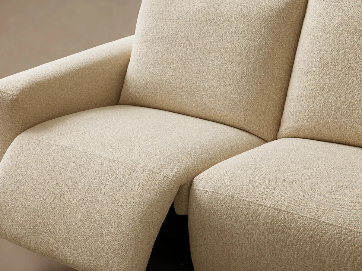 Brennan Four-Piece Motion Sectional in cream-colored textured fabric, viewed straight on against a light tan wall.