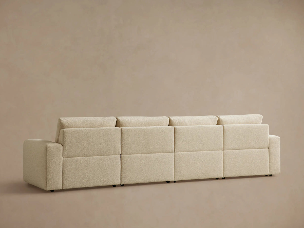 Light beige Brennan Four-Piece Motion Sectional sofa, right section reclined with footrest extended, against a plain wall.