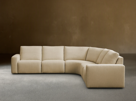 Brennan Five-Piece Motion Corner Sectional: light beige L-shaped sofa with curved corner against a neutral wall, wood floor.