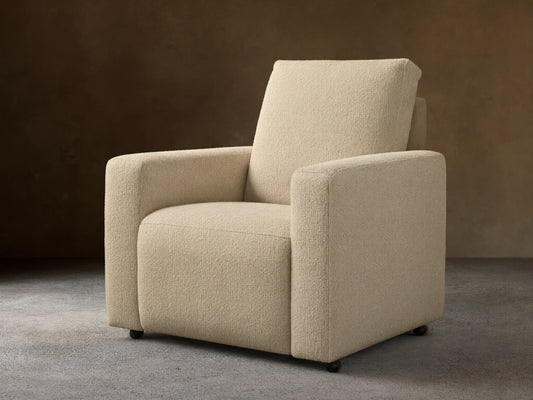 Brennan Motion Recliner in light beige textured fabric, an upright armchair with wide arms, on a wooden floor.