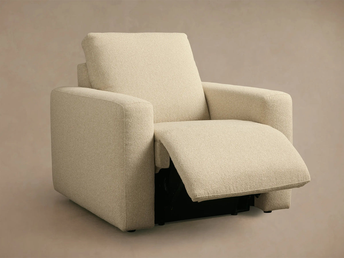 Light beige Brennan Motion Recliner, in textured fabric, seen from the back and side, featuring a modern, blocky design.
