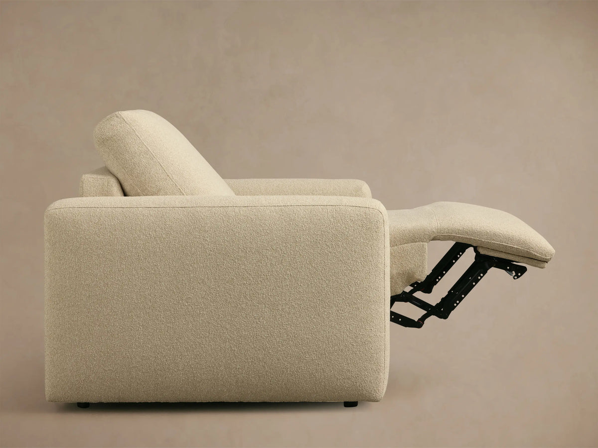 Light beige textured Brennan Motion Recliner, front quarter view, with its footrest extended, revealing black motion mechanism.