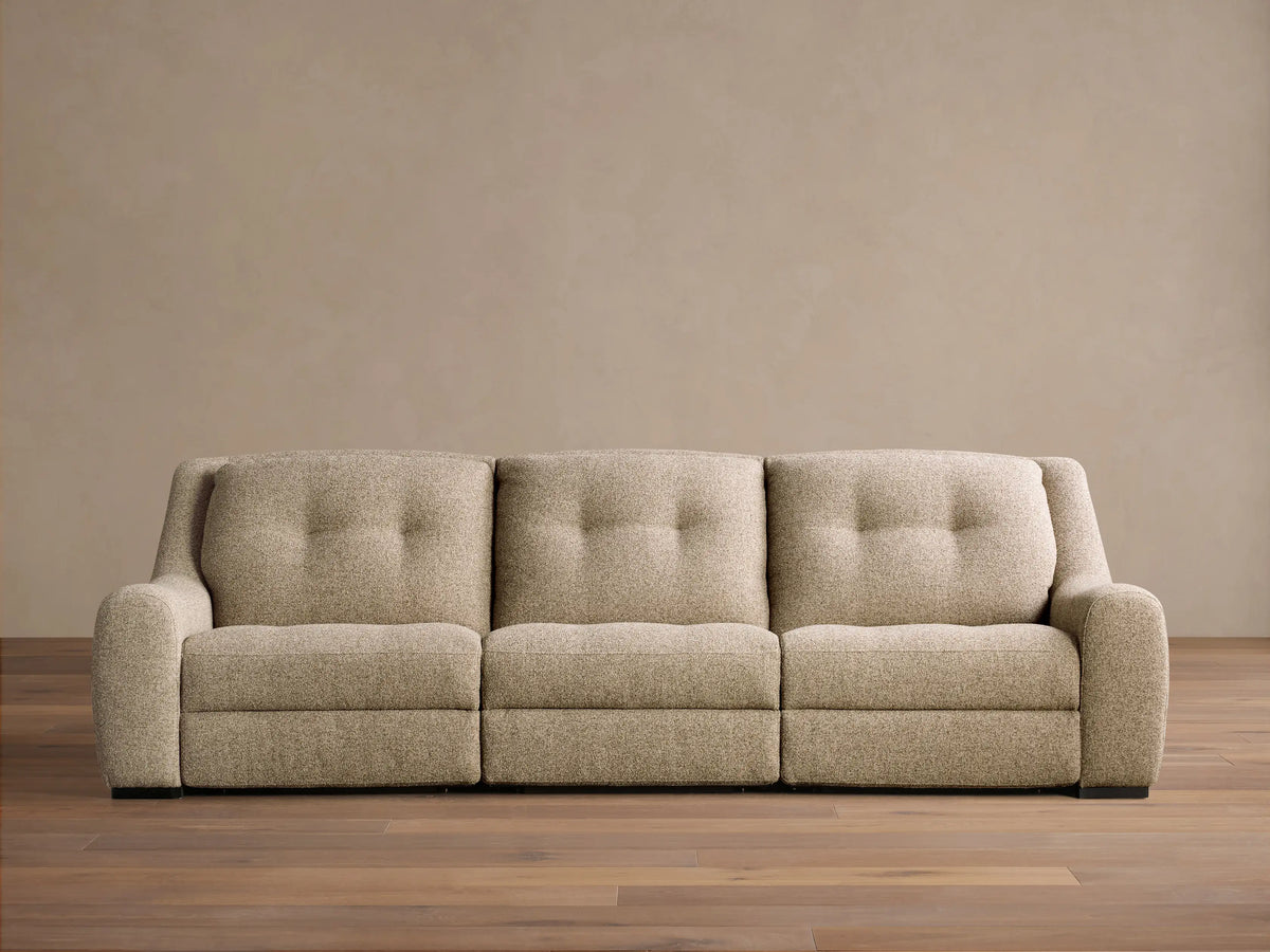 Front view of the light beige textured Perry Three-Piece Motion Sofa, featuring three seats with button-tufted back cushions.