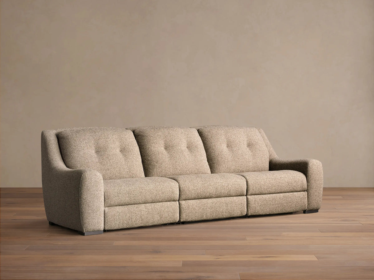 Front view of the light beige textured Perry Three-Piece Motion Sofa, featuring three seats with button-tufted back cushions.