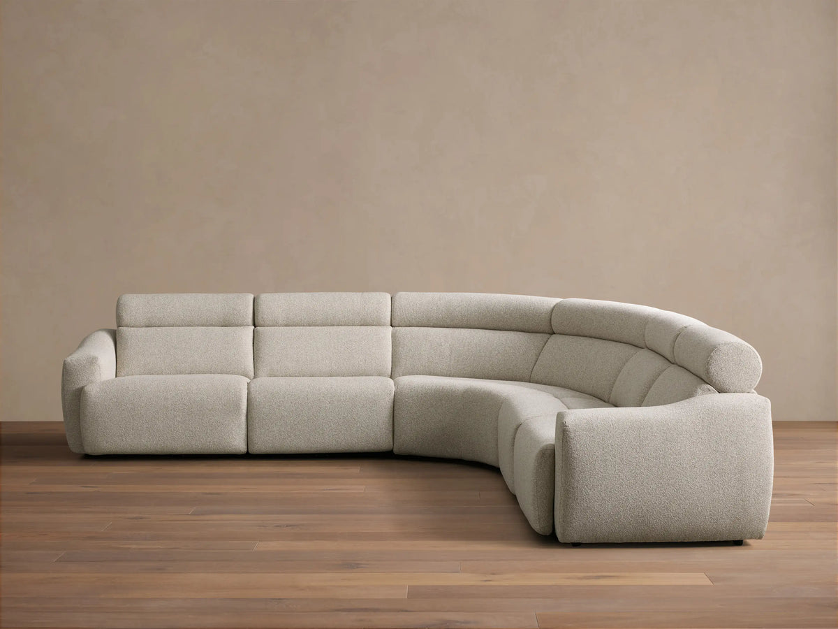 Front view of the light beige Fia Five-Piece Motion Corner Sectional, a curved sofa with textured fabric and segmented cushions.