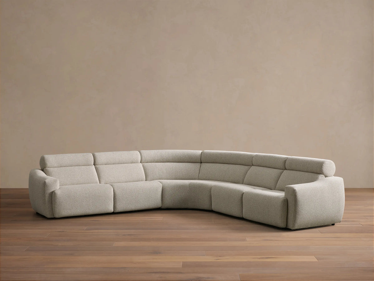 Front view of the light beige Fia Five-Piece Motion Corner Sectional, a curved sofa with textured fabric and segmented cushions.