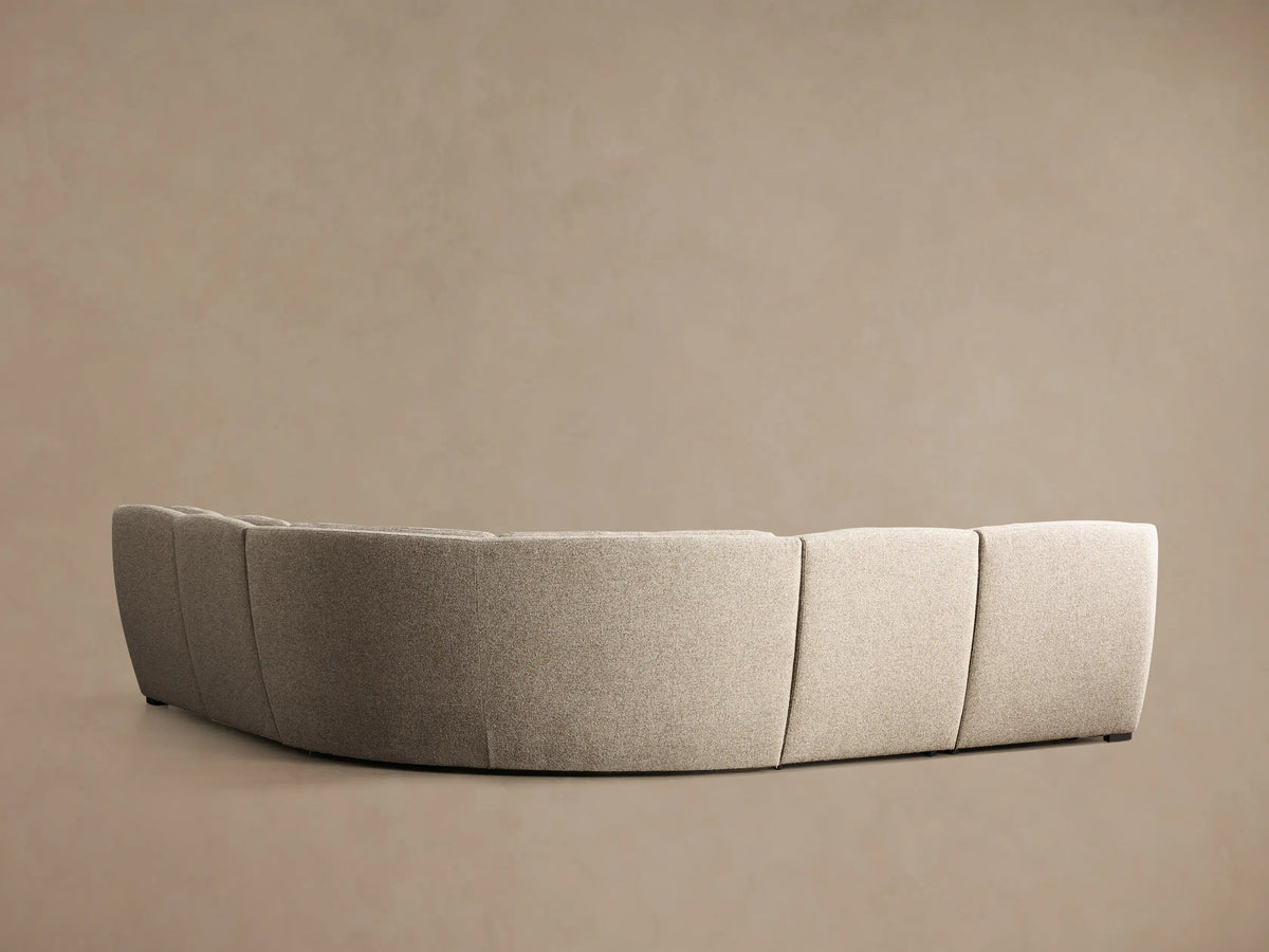 Front-side view of a light greige textured Perry Five-Piece Motion Corner Sectional with tufted cushions, one section reclined.