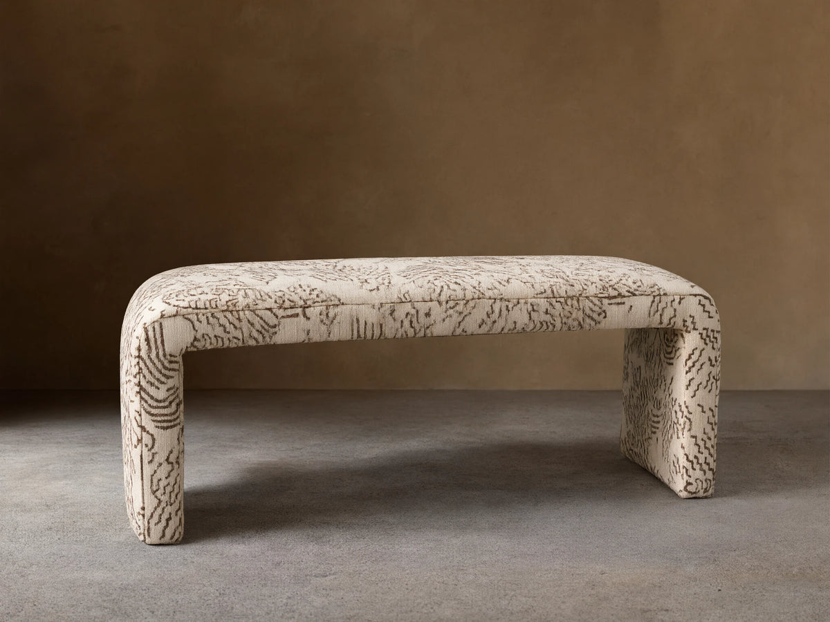 Ryan Bench, U-shaped, fully upholstered in cream fabric with dark brown abstract squiggle pattern, on a wood floor.