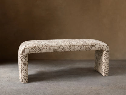 Ryan Bench, U-shaped, fully upholstered in cream fabric with dark brown abstract squiggle pattern, on a wood floor.
