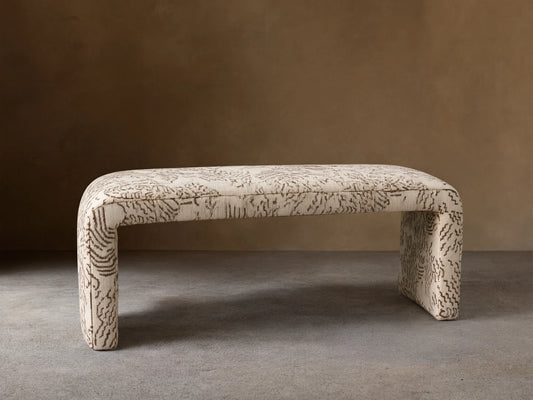 Ryan Bench, U-shaped, fully upholstered in cream fabric with dark brown abstract squiggle pattern, on a wood floor.
