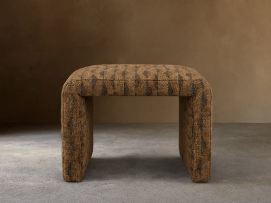 Front view of the brown upholstered Ryan Petite Ottoman with a dark geometric pattern and rounded edges.