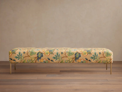 Rectangular Tilton Bench upholstered in tan floral fabric with blue, green, yellow pattern, on slender gold legs.