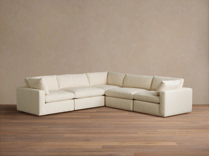 Creamy white Beale Five-Piece Corner Sectional sofa, L-shaped, on a wood floor against a beige wall. Plush textured fabric.