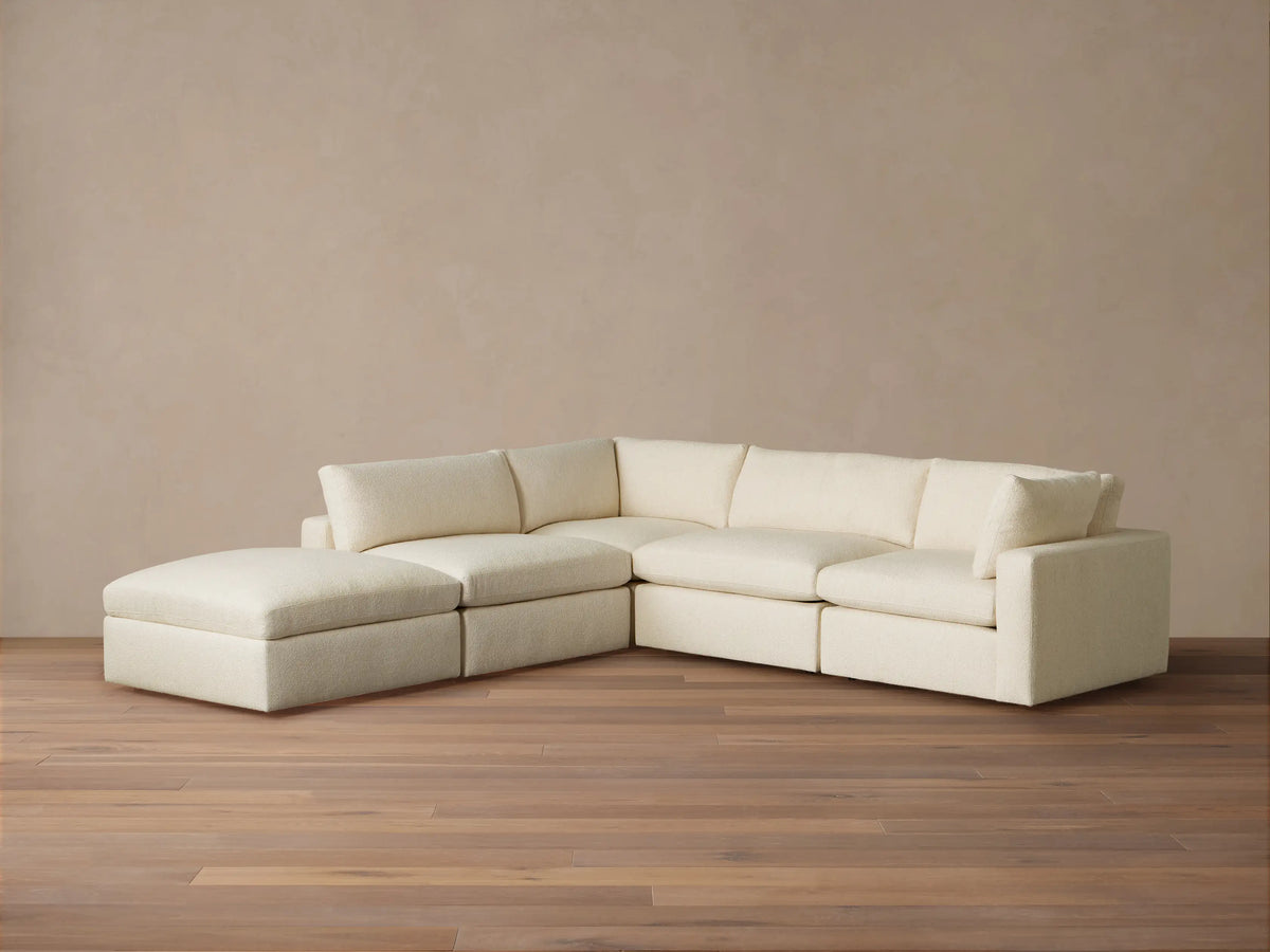 Beale Five Piece Sectional, cream L-shaped modular couch with chaise on left, against a light wall & wood floor.