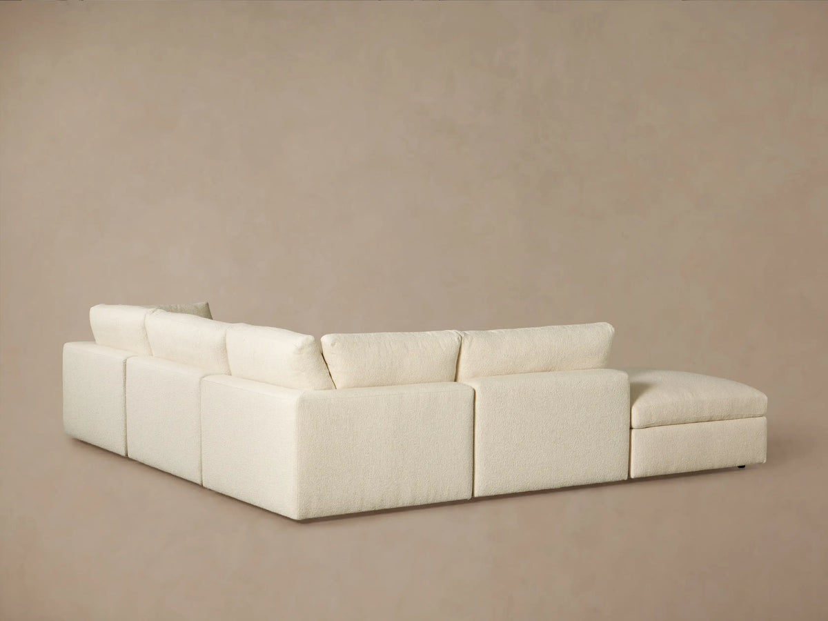 Close-up of a cream-colored Beale Five Piece Sectional sofa, featuring plush, textured boucle fabric on soft seat and back cushions.