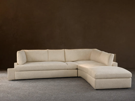 Beale Five Piece Sectional, cream L-shaped modular couch with chaise on left, against a light wall & wood floor.