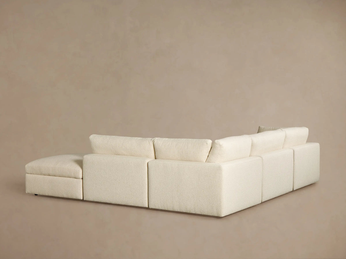 Angled close-up of Beale Five Piece Sectional in cream bouclé fabric, showing plush seat and unique curved back cushion.