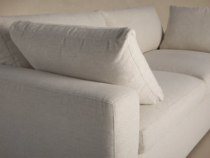 Rear left side view of the cream Beale Sofa, showing plush back cushions and a wide, boxy base.
