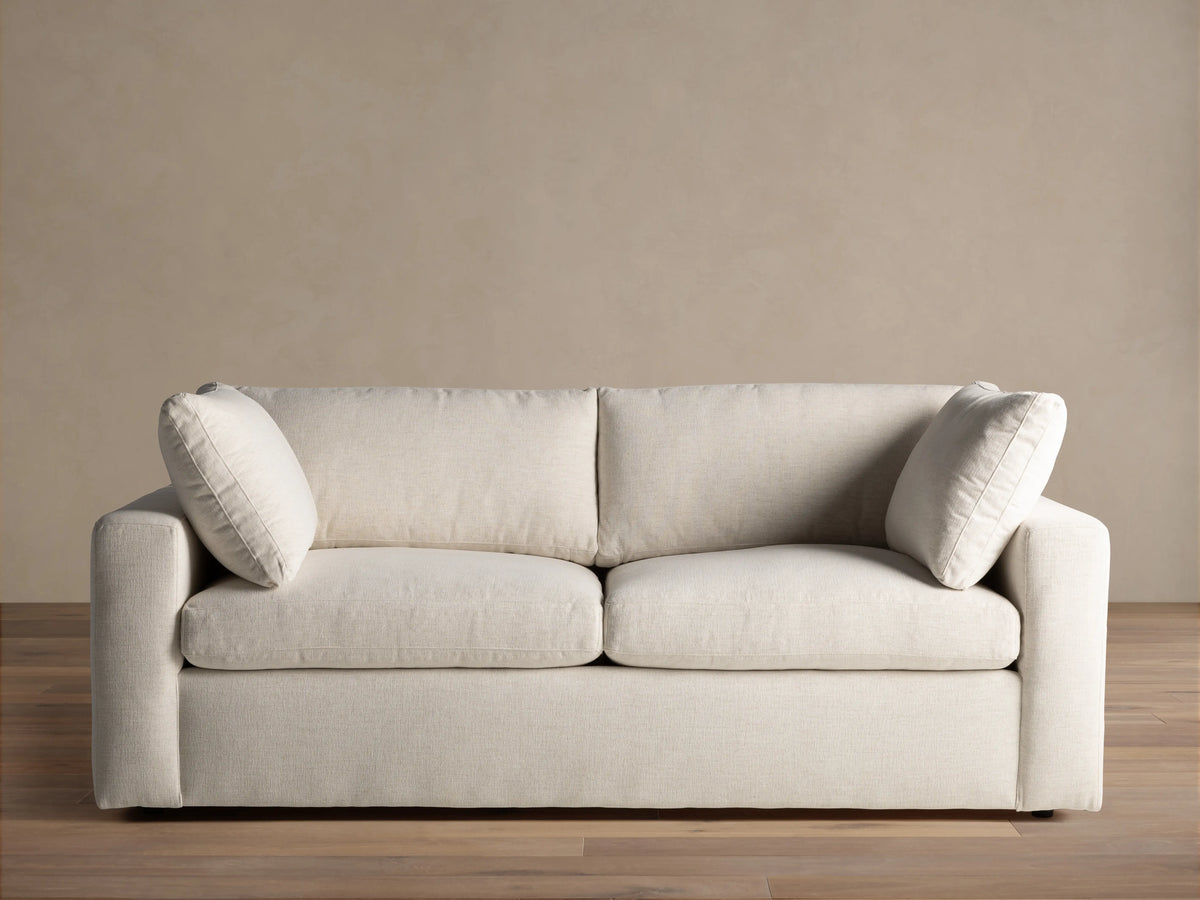Close-up of the cream Beale Sofa, highlighting the textured fabric on the armrest, a plush back cushion, and a seat cushion.