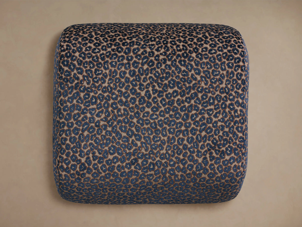 Close-up of Fresno Ottoman upholstered in a blue and beige leopard print fabric, showing its rounded top and side.