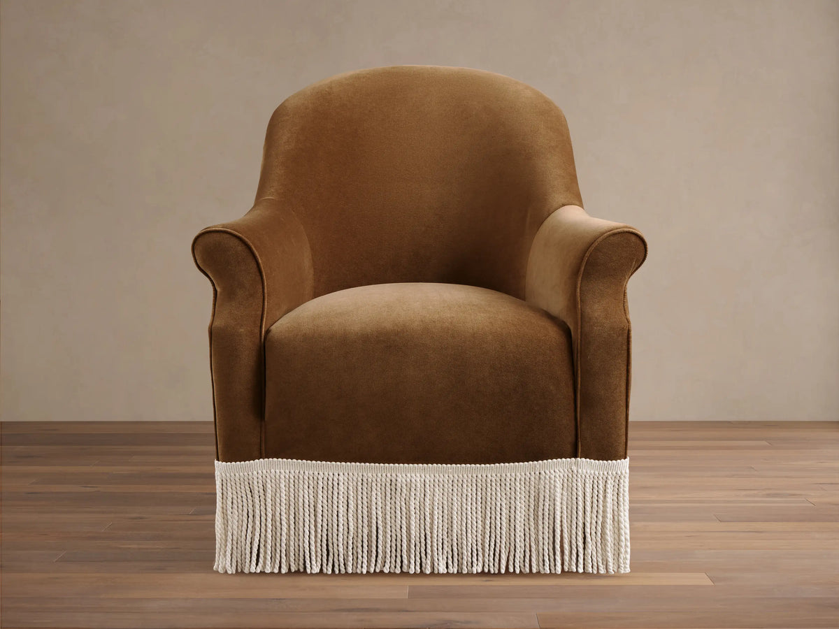 Front view of a caramel Augustus Chair with Fringe, featuring rolled arms and a cream fringe along the bottom base.