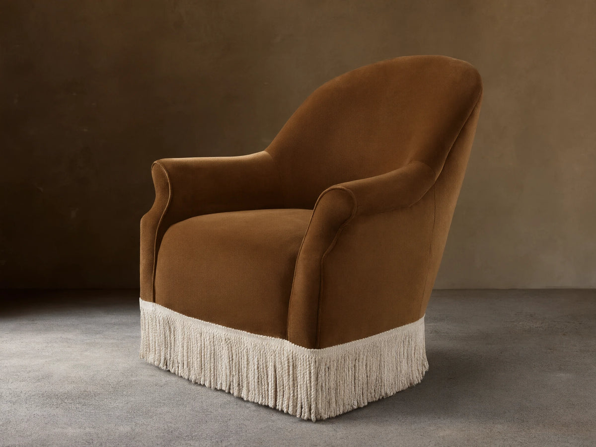 Front view of a caramel Augustus Chair with Fringe, featuring rolled arms and a cream fringe along the bottom base.