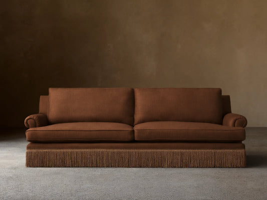 Front view of the brown McKinley Sofa with Fringe, featuring rolled arms, plush cushions, and a distinctive fringe along the base.