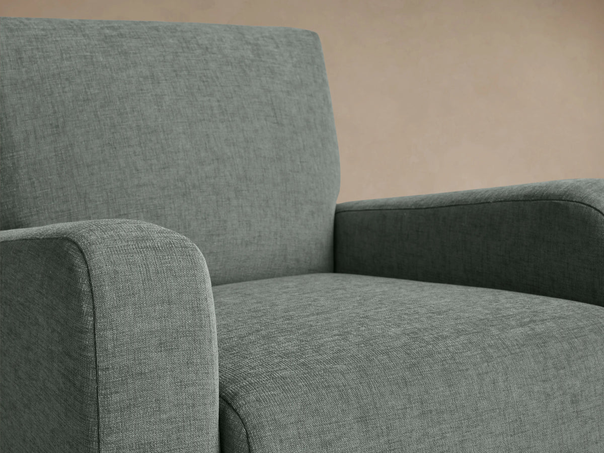 Kershaw Chair in soft green fabric, featuring rounded arms, dense cushioned seat and backrest, on dark wooden legs.