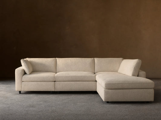 Beale Four-Piece Bumper Sectional, light cream textured fabric, L-shaped with a left-facing chaise on a wood floor.