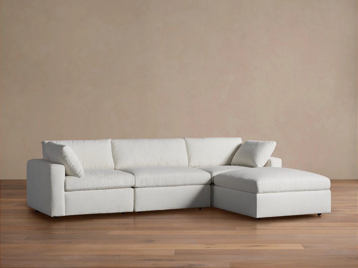 Casual Beale Four-Piece Sectional in light off-white fabric with three sections and a right-facing chaise, on wood floor.