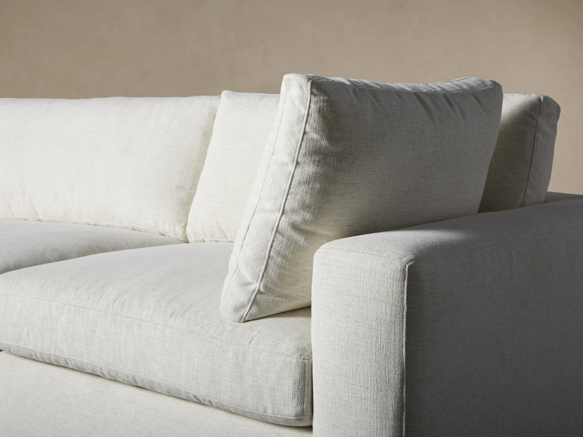 Beale Four-Piece Sectional in light gray fabric, L-shaped, with a right-facing chaise, on a wood floor against a tan wall.