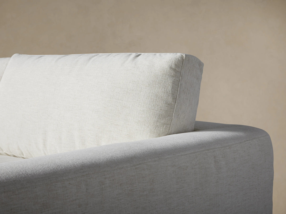 Close-up of the Beale Four-Piece Sectional in light beige textured fabric, showing soft seat and back cushions, and a wide armrest.