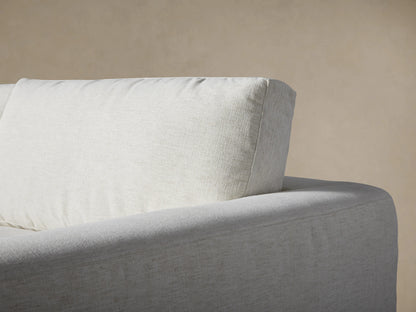 Close-up of the Beale Four-Piece Sectional in light beige textured fabric, showing soft seat and back cushions, and a wide armrest.