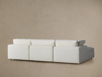 Beale Four-Piece Sectional close-up. Light gray textured fabric armrest and soft back cushion with a slight wrinkle, beige wall.