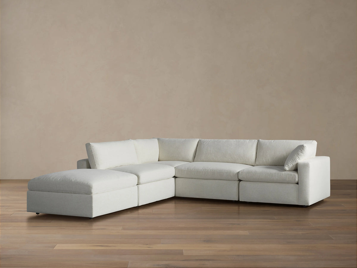 Beale Five Piece Sectional sofa in light fabric with left-facing chaise lounge on a wood floor against a brown wall.