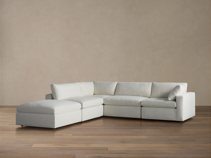Beale Five Piece Sectional sofa in light fabric with left-facing chaise lounge on a wood floor against a brown wall.