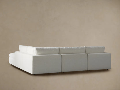 Beale Five Piece Sectional, close-up of a textured light beige fabric backrest & seat with subtle wrinkles against a tan wall.