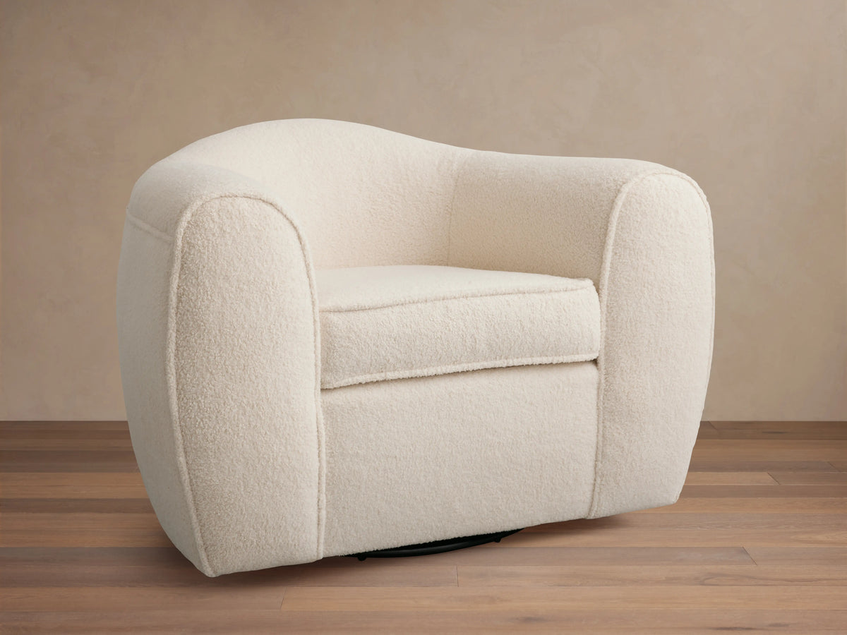 Cream-colored Barret Chair with plush, rounded armrests and backrest. Features a soft fabric texture and a solid base for swivel rotation.