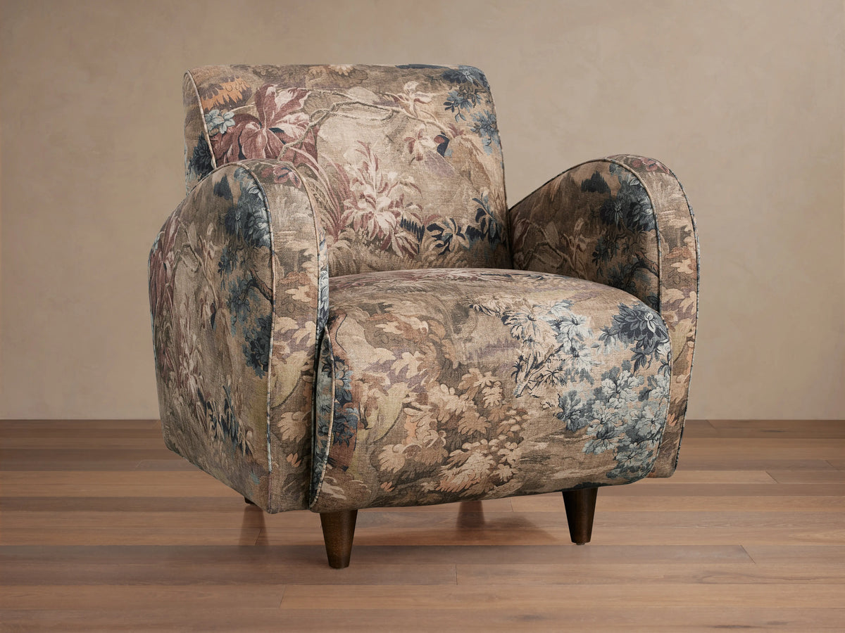 A Myrtle Chair with floral-patterned Avery Cashmere fabric and Avery Mink welt detail, featuring a plush seat, rounded arms, and tapered legs on a wooden floor.