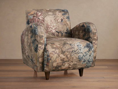 A Myrtle Chair with floral-patterned Avery Cashmere fabric and Avery Mink welt detail, featuring a plush seat, rounded arms, and tapered legs on a wooden floor.