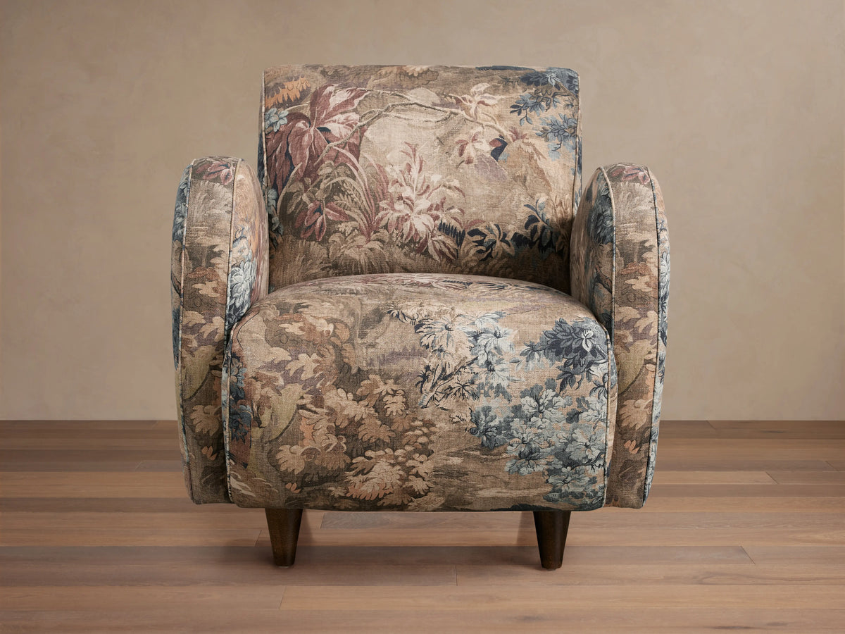 A Myrtle Chair with floral-patterned Avery Cashmere fabric and Avery Mink welt detail, featuring a plush seat, rounded arms, and tapered legs on a wooden floor.