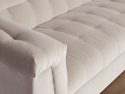 Beige Cameran Sofa with tufted backrest and armrests, placed on a wooden floor against a neutral wall.