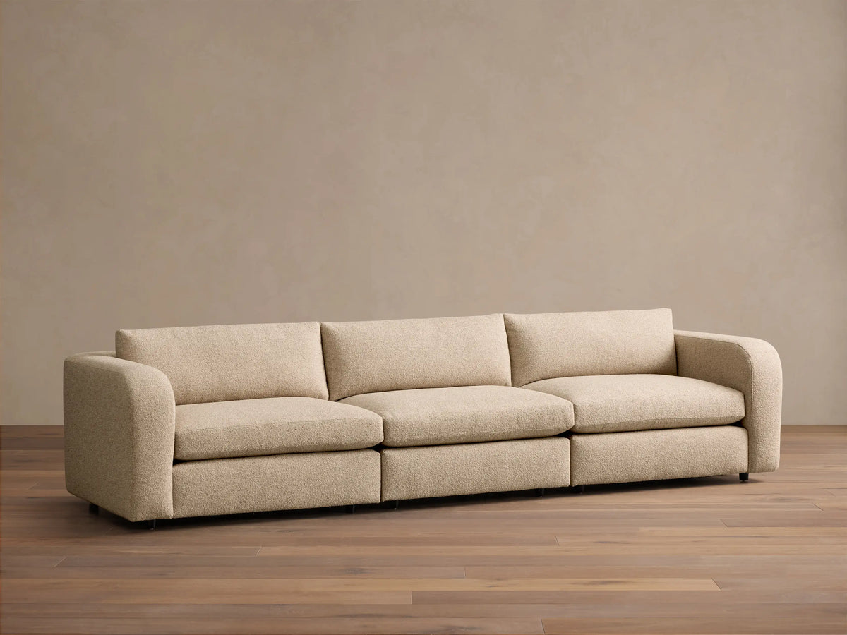 Close-up of the cream textured fabric on the armrest and back cushion of the Stiles Three-Piece Modular Sofa.