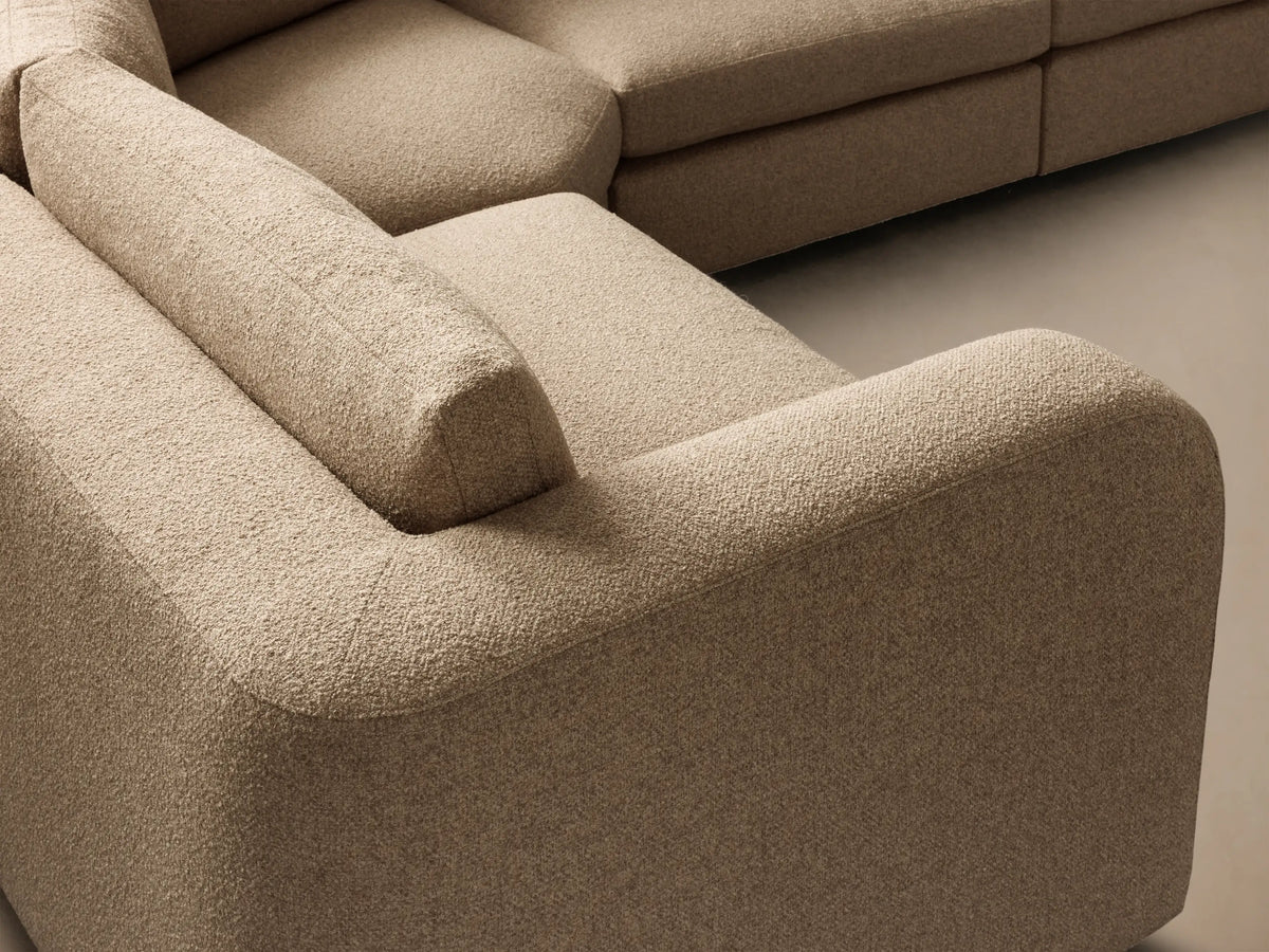 Front view of the tan textured woven fabric Stiles Four-Piece Sectional, with low-profile arms and back cushions, arranged in an L-shape.