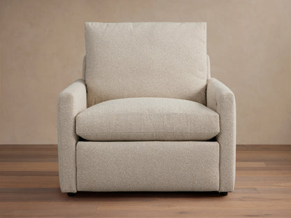 Kipton Motion Recliner in light beige fabric with slim rectangular arms, plush seat, and back cushion on a wooden floor.