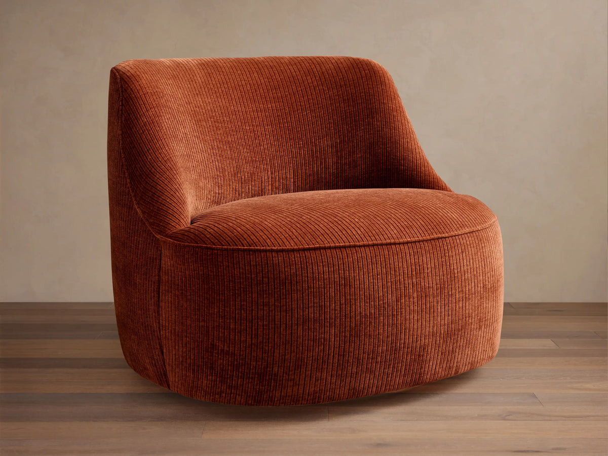 Sonny Swivel Chair upholstered in rust orange ribbed corduroy fabric, angled front-left, with a curved back and round base.