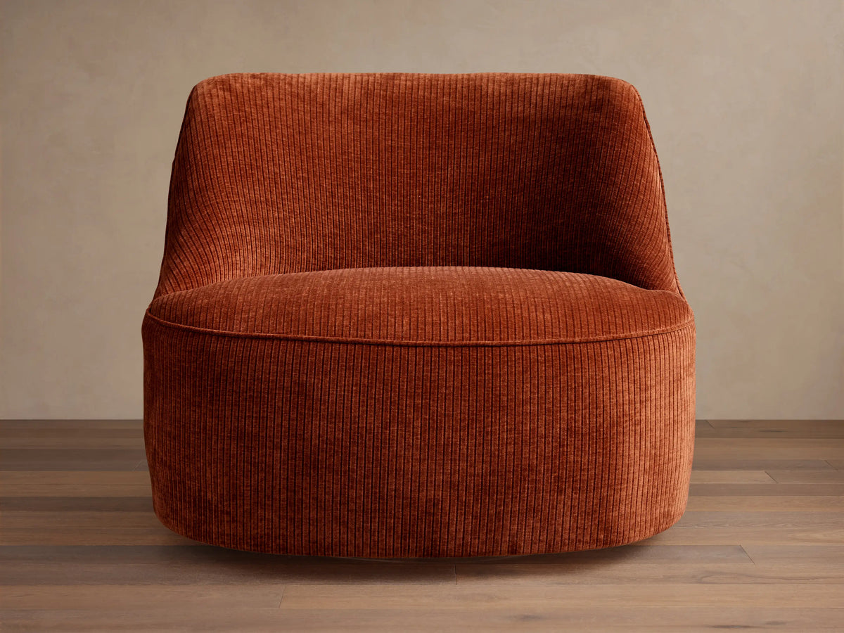 Sonny Swivel Chair upholstered in rust orange ribbed corduroy fabric, angled front-left, with a curved back and round base.