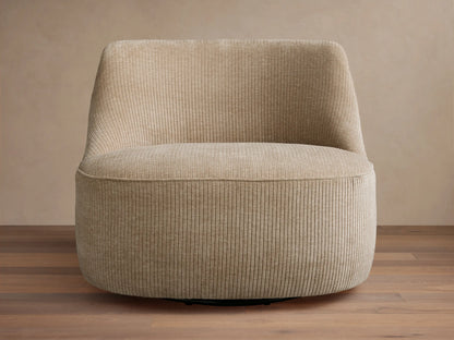 Sonny Swivel Chair, upholstered in light beige ribbed fabric, slightly angled on a wooden floor against a light wall.