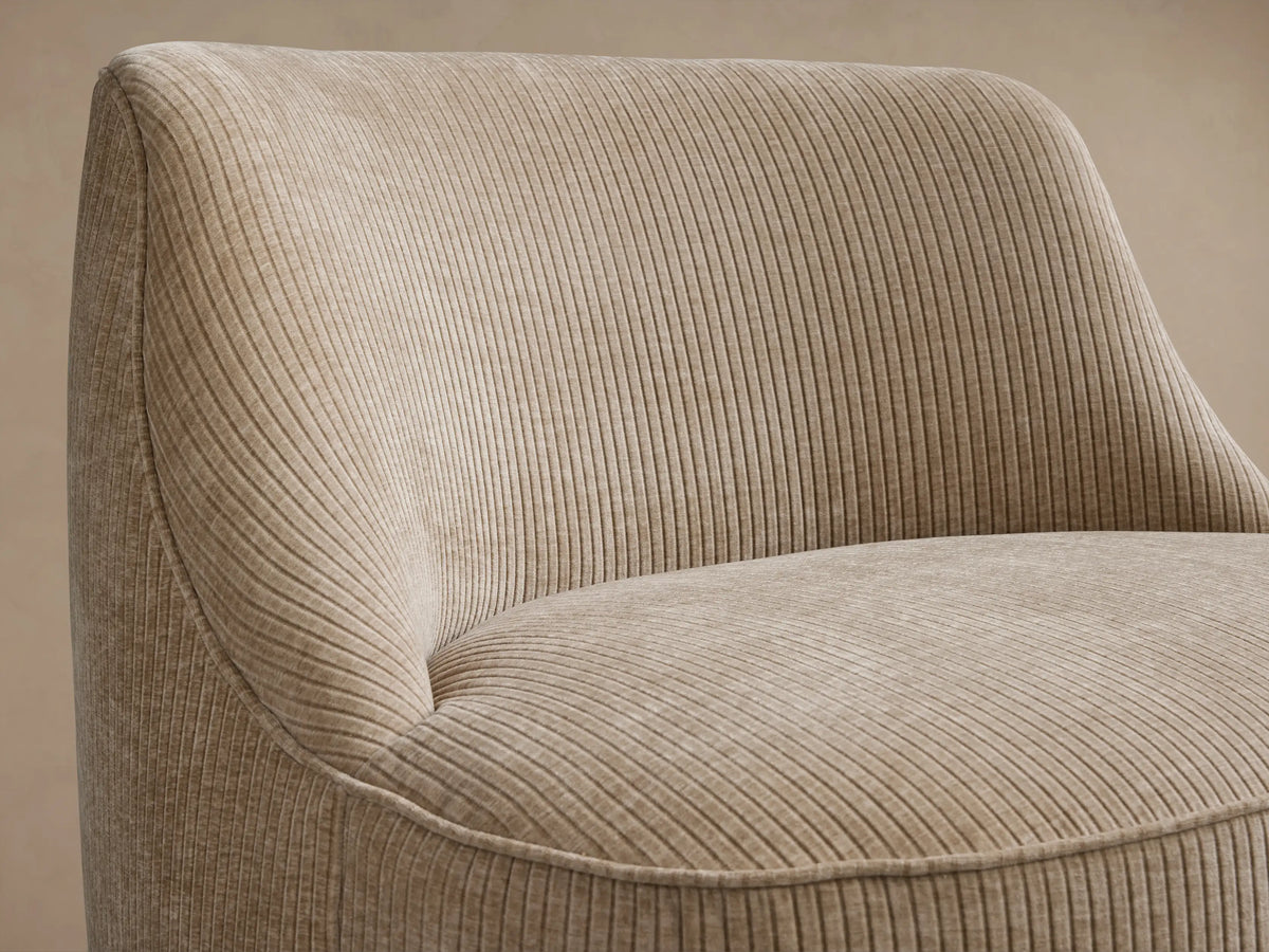 Sonny Swivel Chair in a ribbed, light beige fabric. Rounded, armless chair with curved back, front-facing on wood floor.