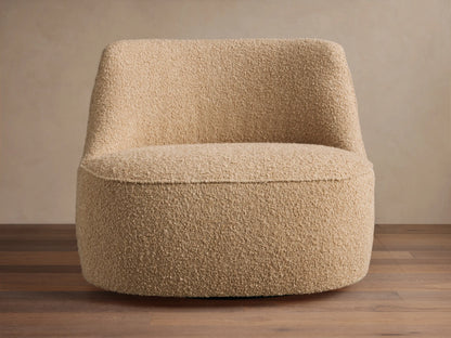 Sonny Swivel Chair, rounded, armless, light beige bouclé fabric, on wood floor against a neutral wall.
